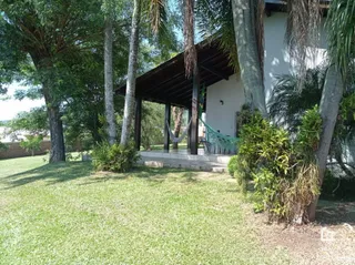 Fachada de uma casa com gramado e árvores no quintal.