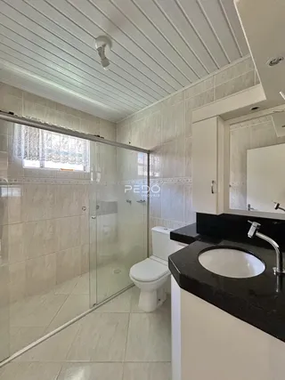 Foto de um banheiro com box de vidro e revestimento cerâmico.