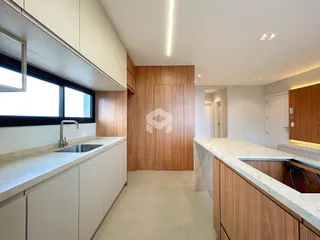 Vista da cozinha moderna com armários de madeira e bancadas claras.