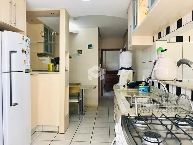 Vista interna de uma cozinha com armários brancos e piso cerâmico.
