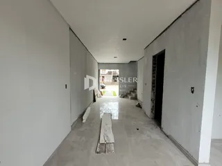 Corredor interno de uma residência em construção com paredes de concreto aparente.