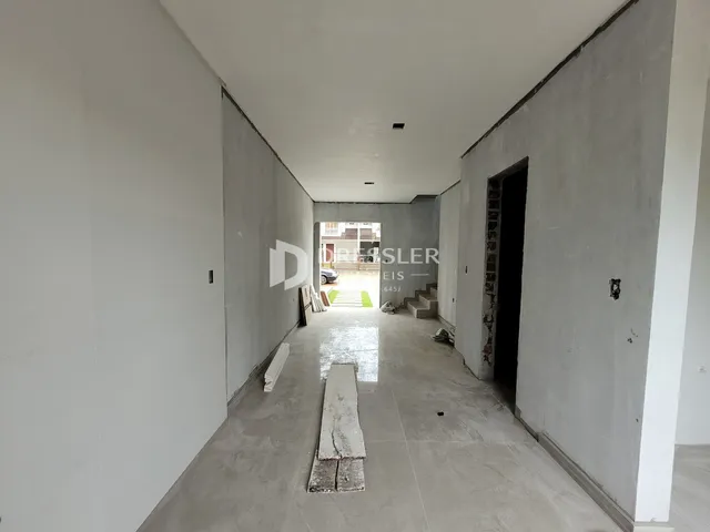 Corredor interno de uma residência em construção com paredes de concreto aparente.