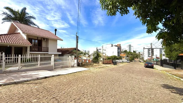 Vista da fachada de uma casa em Lajeado, Brasil, com cerca e área pavimentada na frente.
