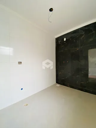 Interior de um cômodo com paredes brancas e uma parede de destaque escura.