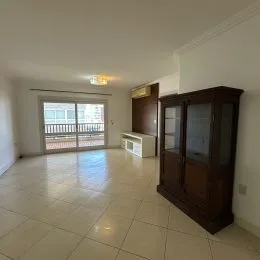 Sala de estar com piso de cerâmica clara e armários de madeira no fundo.