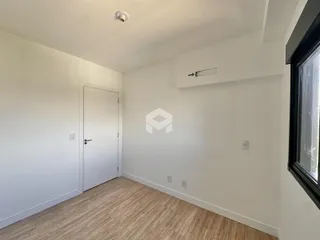 Imagem de um ambiente interno com paredes brancas e piso de madeira clara.