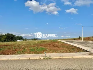 Vista externa de um terreno aberto com grama seca sob um céu azul.