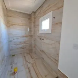 Corredor interno com revestimento de pedra clara nas paredes e piso.