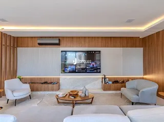 Sala de estar com painel de madeira e televisão montada na parede.