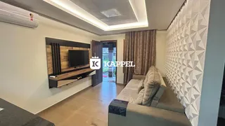 Sala de estar com sofá e televisão montada na parede em um apartamento.