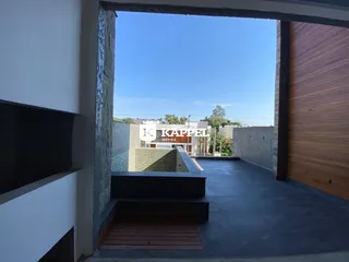 Vista externa de um pátio com piso escuro e estrutura de concreto.
