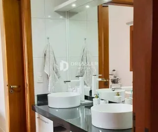 Vista de um banheiro com pias brancas e revestimento branco.
