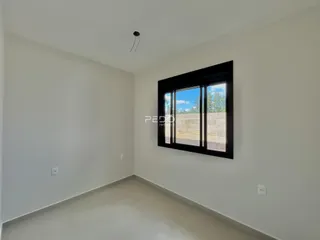 Ambiente interno de uma sala com paredes brancas e uma grande janela.