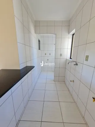 Corredor interno com piso e paredes brancas de cerâmica.