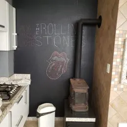Foto de uma parede escura com um vaso sanitário branco.
