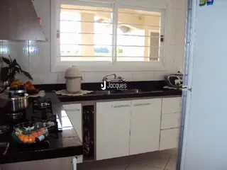 Vista da cozinha com armários brancos e bancada escura.