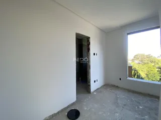 Interior de uma sala com paredes brancas e piso de concreto aparente.