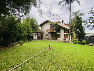 Vista externa de uma residência com jardim gramado e vegetação ao redor.