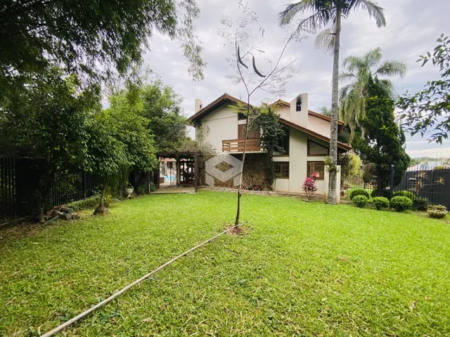 Vista externa de uma residência com jardim gramado e vegetação ao redor.