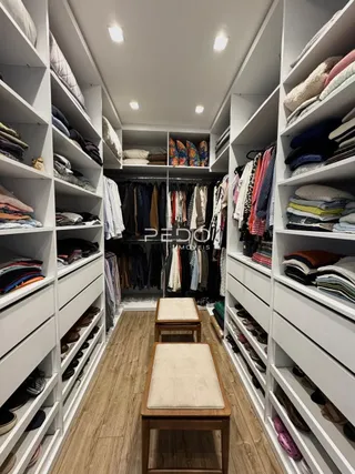 Hall com estantes brancas preenchidas com roupas.