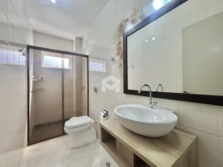 Banheiro moderno com revestimento cerâmico e box de vidro.