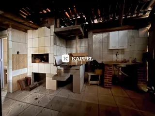Ambiente interno com estrutura de madeira exposta e revestimento de azulejos na cozinha.
