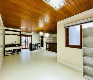 Ambiente interno com teto de madeira e piso claro em uma residência.