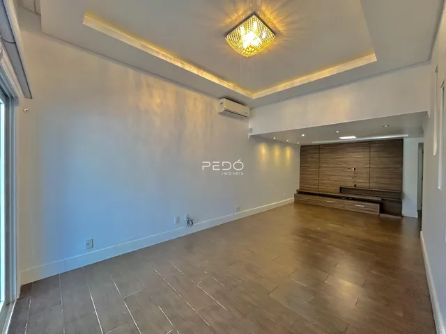 Ambiente interno de uma sala de estar com piso de madeira e teto alto.