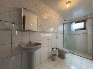 Banheiro com piso cerâmico e paredes revestidas de azulejos brancos.