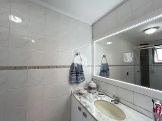 Banheiro com revestimento de cerâmica branca e espelho no ambiente.