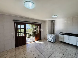 Interior de uma sala com piso de cerâmica e portas de madeira que dão acesso ao exterior.
