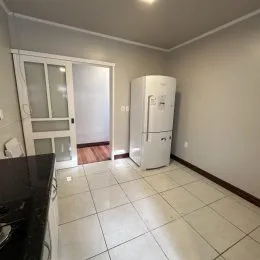 Ambiente interno com piso de cerâmica e geladeira branca em um imóvel.