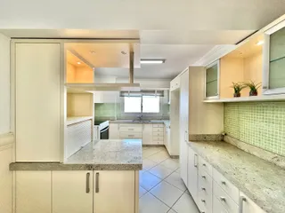Vista interna de uma cozinha com armários brancos e revestimento verde claro.