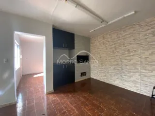 Foto de um corredor interno com piso de ladrilho avermelhado e teto com dutos expostos.