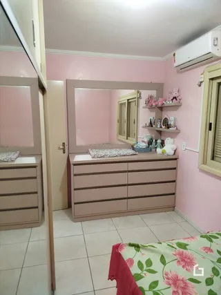 Um quarto com paredes rosa claro e armário de madeira.