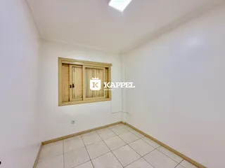 Foto interna de um cômodo com piso de cerâmica e janela de madeira.