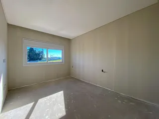 Foto de um cômodo vazio com piso de concreto e uma janela.