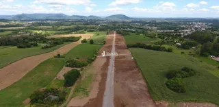 Vista aérea de uma área rural com campos e uma estrada de terra.