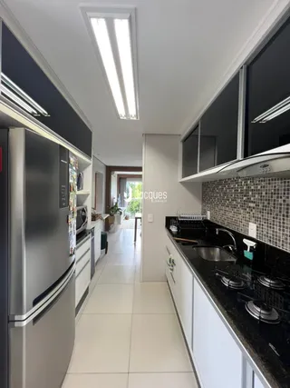 Vista interna de uma cozinha moderna com armários escuros e piso claro.