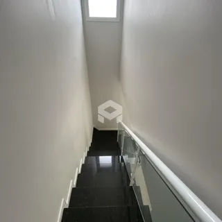Corredor com escadaria e guarda-corpo de vidro em um imóvel.