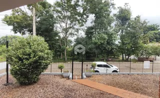 Vista externa de uma propriedade com cerca e vegetação densa.