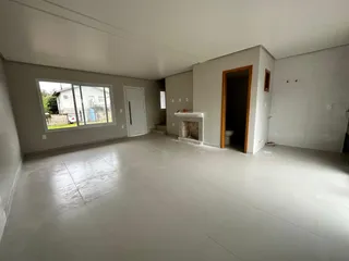 Ambiente interno amplo com piso claro e grandes janelas.