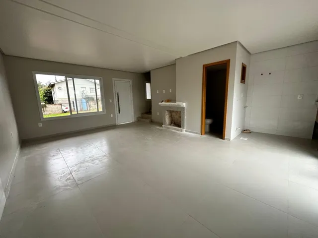 Ambiente interno amplo com piso claro e grandes janelas.