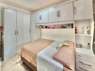 Quarto com armários brancos e cama em um imóvel no Brasil.