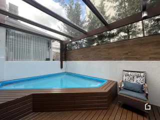 Vista da piscina externa com deck de madeira.
