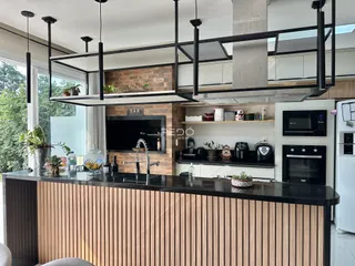 Vista da cozinha moderna com ilha e bancada escura.