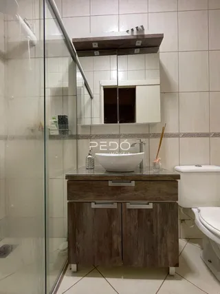 Banheiro com revestimento cerâmico e divisória de vidro.