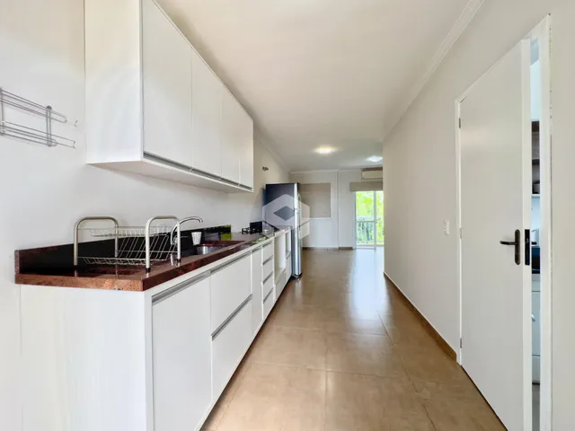 Vista de uma cozinha com armários brancos e bancada escura em um imóvel no Brasil.