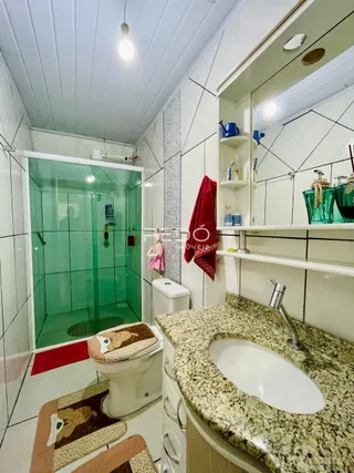 Foto de um banheiro com revestimento cerâmico e box de vidro.