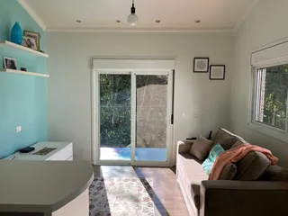 Sala de estar com sofá e porta de vidro que dá acesso ao exterior.